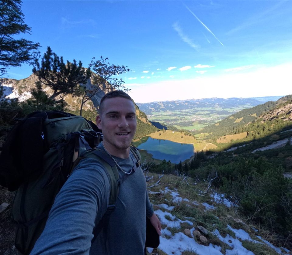 Sven during a mountain hike with a view over a lake and mountains